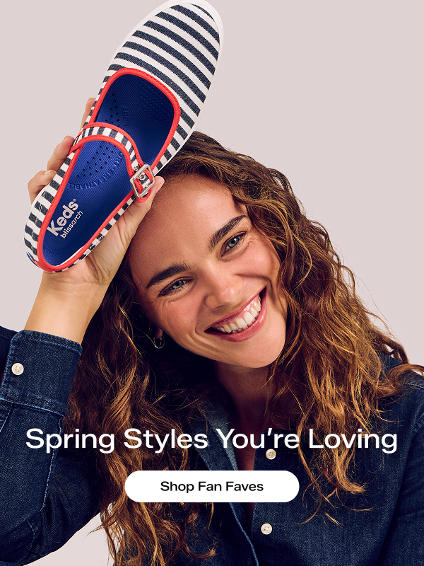 A woman smiling, looking off to the side, she is holding up the Maisie Mary Jane Printed Stripe Twill flat in black/natural above her head. Text on the image says Spring Styles You’re Loving. Shop Fan Faves.