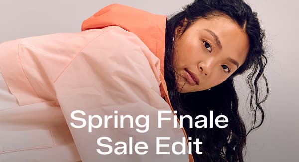 A woman wearing an ombre orange wind breaker jacket paired with the BlissMove Knit Ease Slip-Ons in neon coral. A callout in the corner of the image notes that this sneaker was $59.99 and is now on sale for $38.99 for a limited time. Text overlaid on the image says Spring Finale Style Edit.