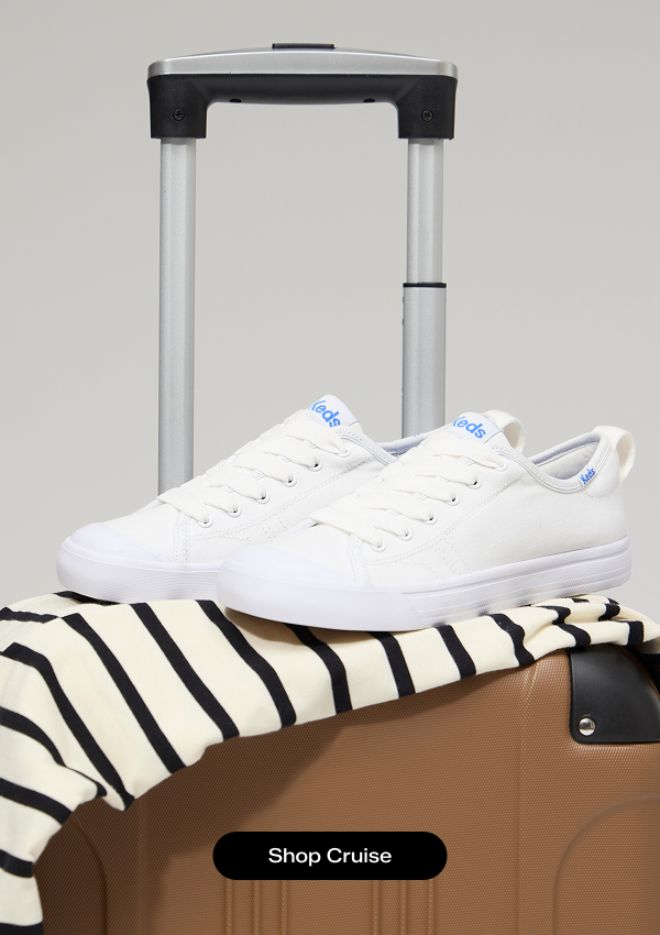A brown spinner suitcase with a white-and-black striped dress and the Cruise Leather Slip-On in white resting on top. Shop the Cruise.