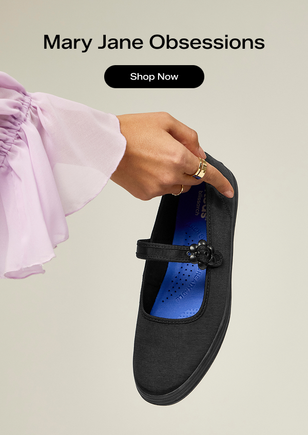 The Maisie Mary Jane in black grosgrain being held up to showcase its flower-shaped buckle. Text above says Mary Jane Obsessions. Shop Now.