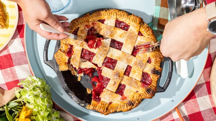 Cherry pie in a cast iron pie pan on a checked tablecloth