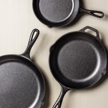 Three cast iron skillets in different sizes on a light background.