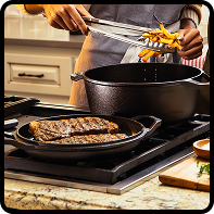  Cast iron skillet and Dutch oven on a stovetop with food being cooked