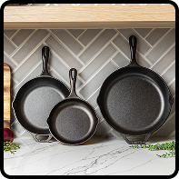 Set of three cast iron skillets in different sizes displayed on a kitchen counter
