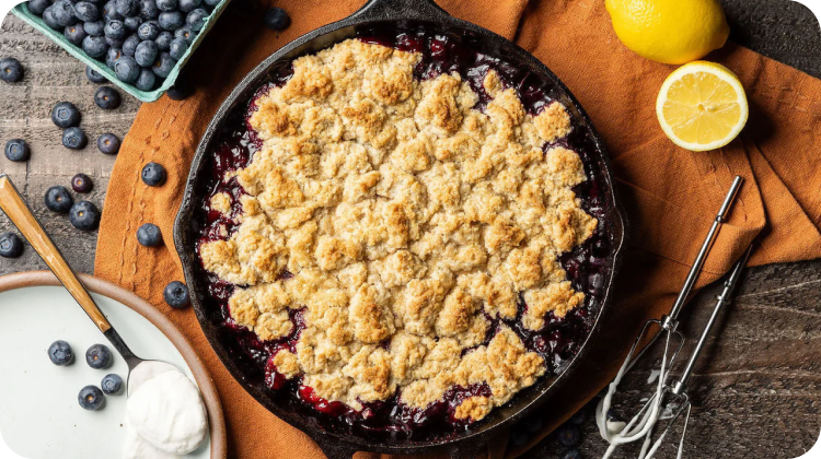 Blueberry cobbler in a cast iron skillet on a wooden table