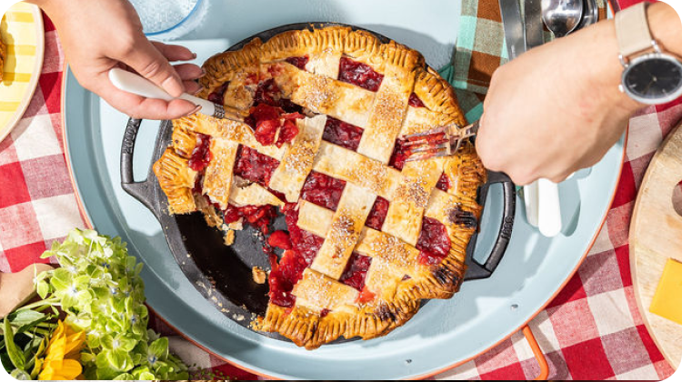 Strawberry pie in a dual-handle skillet on a picnic blanket