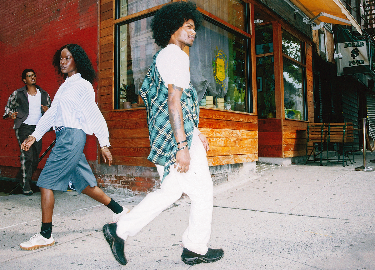 Three models walking in different directions passing by of a corner cafe.