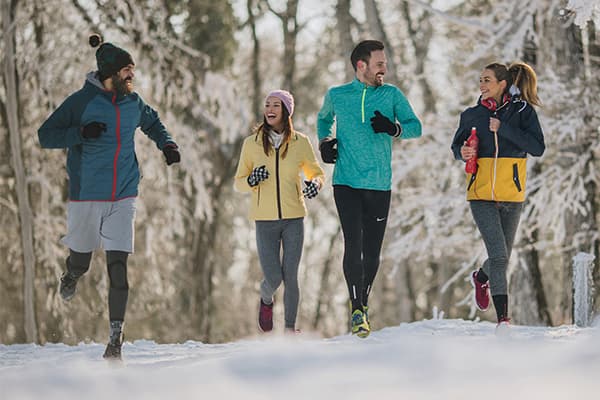 group of men and women running in the snow