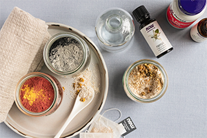 top view of Three DIY Functional Face Mask Powders with a glass vase and NOW essential oils in view