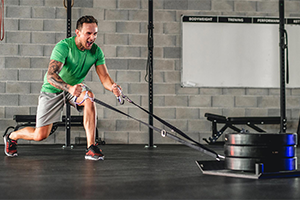 White male in a gym doing a sled pull