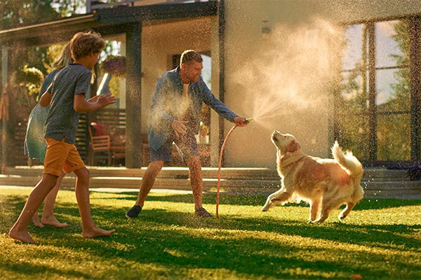 Family Playing together with their dog in the yard with the hose.