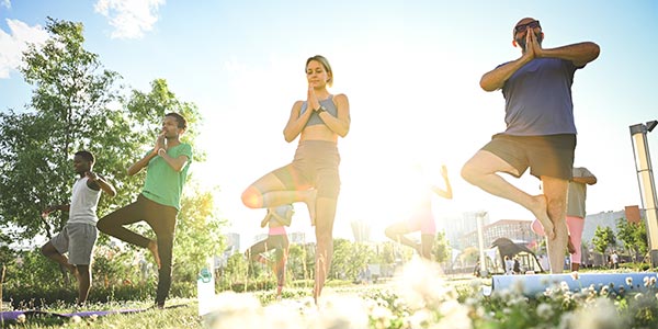 diverse group of people doing yoga outdoors