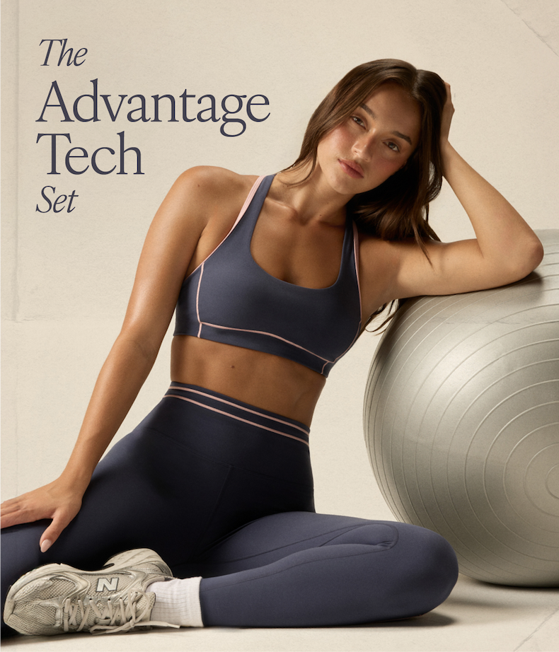 Model wearing navy and pink Advantage Tech sports bra and leggings, seated beside exercise ball.