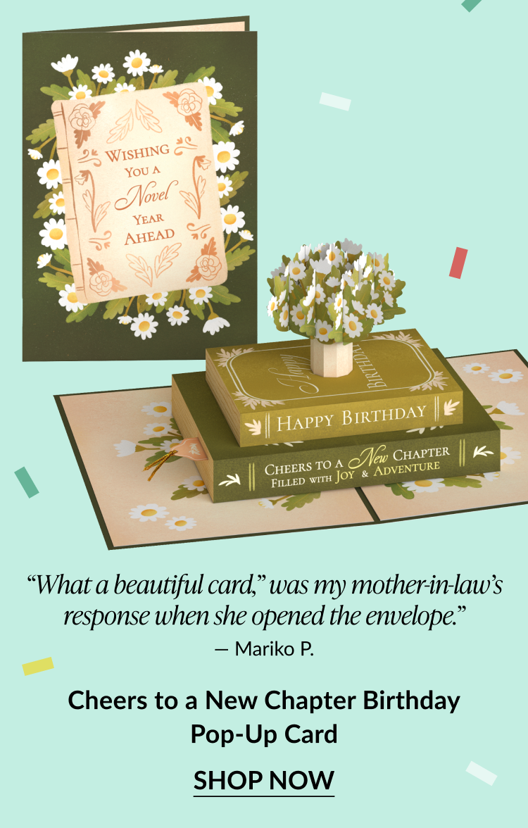 A birthday pop-up card featuring books and text that reads ''cheers to a new chapter.''