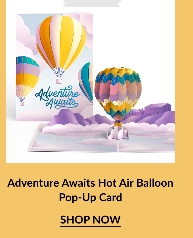 Pastel-colored pop-up card with a scenic landscape and 3D hot air balloon. Cover features multiple balloons with the message Adventure Awaits. Call-to-action below reads Adventure Awaits Hot Air Balloon Pop-Up Card – Shop Now.