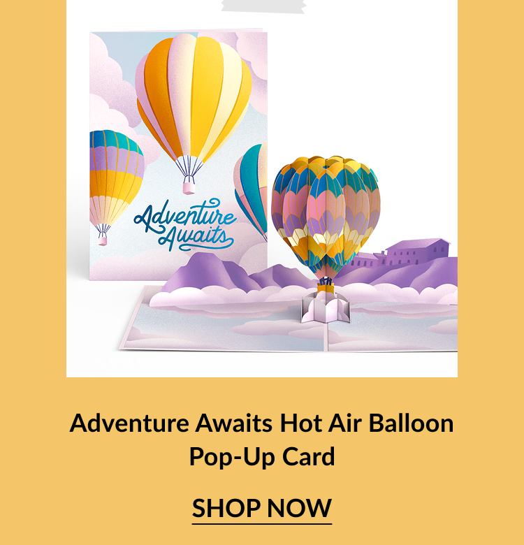 Pastel-colored pop-up card with a scenic landscape and 3D hot air balloon. Cover features multiple balloons with the message Adventure Awaits. Call-to-action below reads Adventure Awaits Hot Air Balloon Pop-Up Card – Shop Now.
