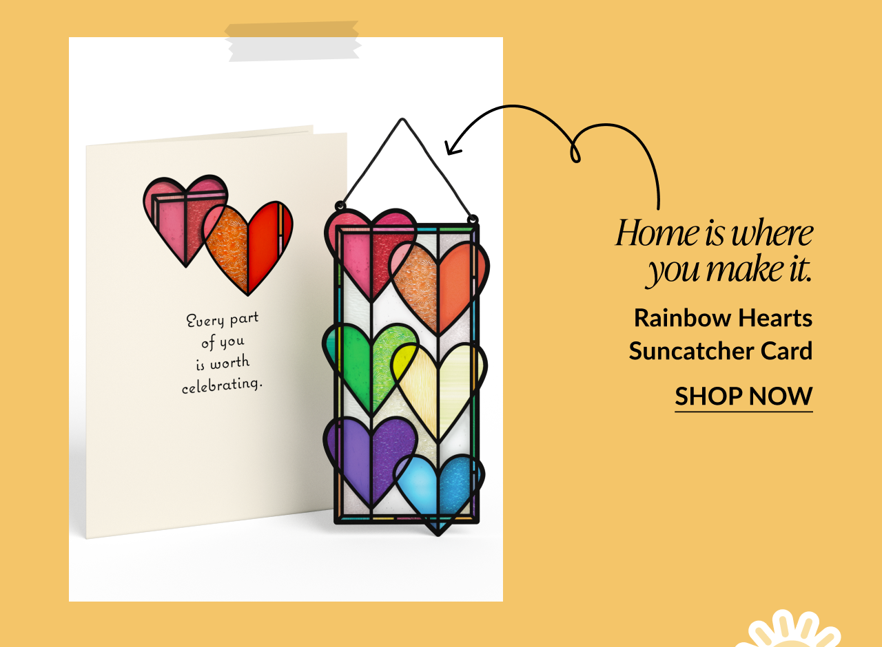 Card with rainbow-colored heart shapes and matching multicolored heart suncatcher. Card reads: 'Every part of you is worth celebrating.' Text below says: 'Home is where you make it. Rainbow Hearts Suncatcher Card.' Button reads 'Shop Now.