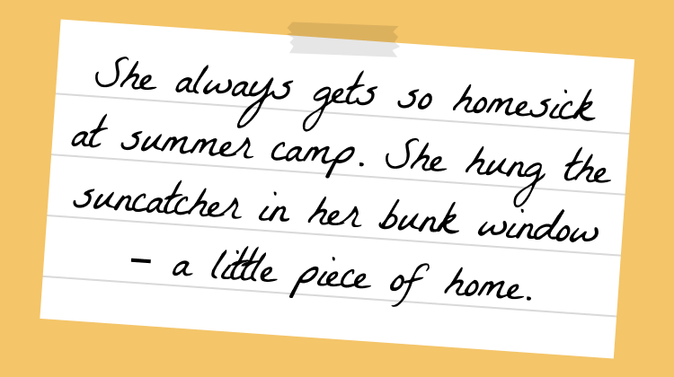 Handwritten note on lined paper with tape and a beach shell sticker, reading: 'She always gets so homesick at summer camp. She hung the suncatcher in her bunk window – a little piece of home.