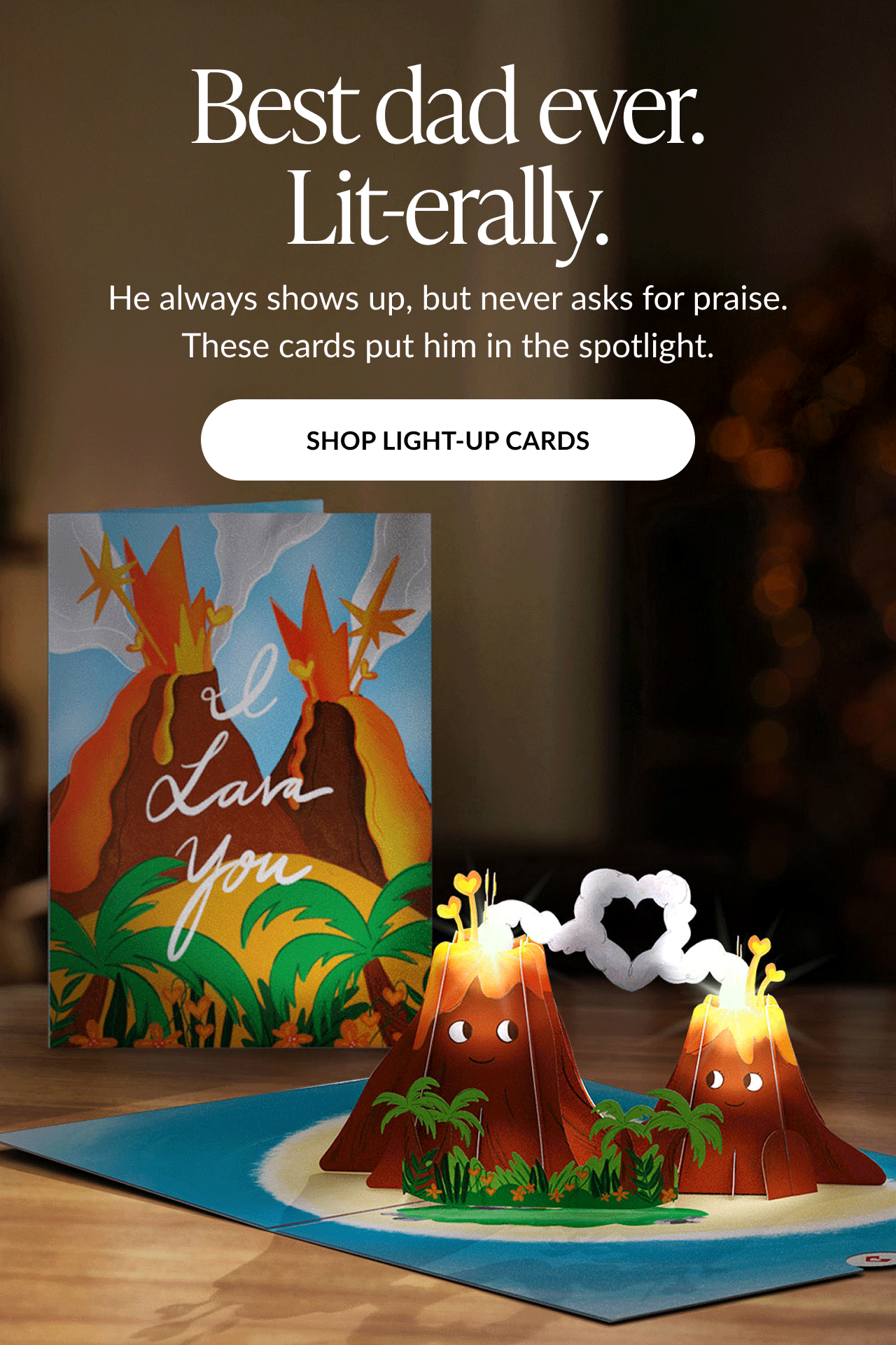Animated image of a Father's Day card featuring two smiling volcanoes with glowing lava and a heart-shaped smoke cloud. Text reads: ''Best dad ever. Lit-erally. He always shows up, but never asks for praise. These cards put him in the spotlight.'' Button text: ''SHOP LIGHT-UP CARDS''.