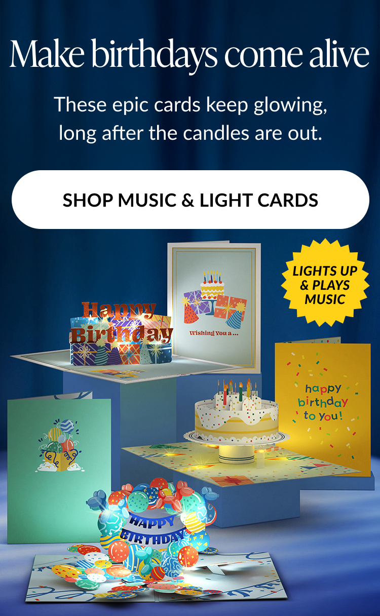 Animated image of several birthday-themed pop-up cards with glowing lights and music icons. Text reads: ''Make birthdays come alive. These epic cards keep glowing, long after the candles are out.'' Button text: ''SHOP MUSIC & LIGHT CARDS''. A yellow starburst badge reads: ''LIGHTS UP & PLAYS MUSIC''.