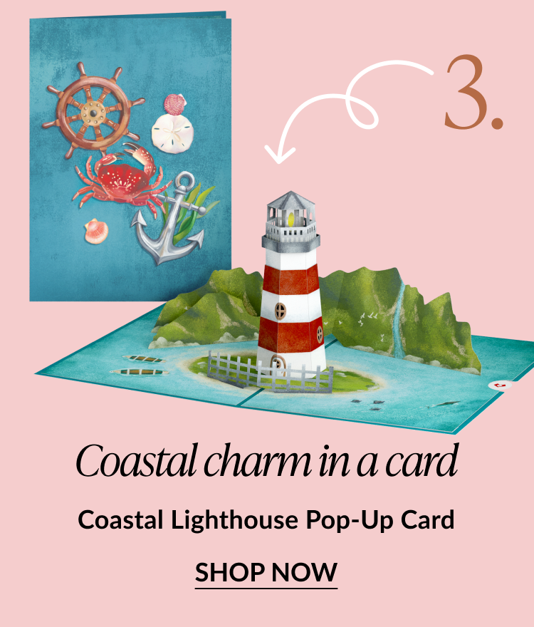Pop-up card featuring a red and white striped lighthouse on a coastal island. Text reads: Coastal charm in a card. Coastal Lighthouse Pop-Up Card. SHOP NOW.