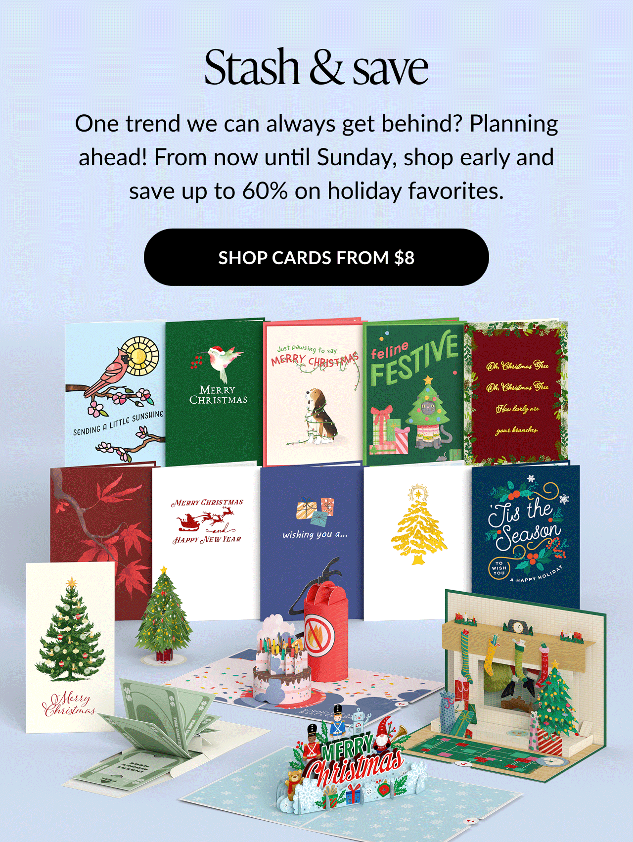 Assortment of festive holiday cards and pop-ups including Christmas trees, stockings by the fireplace, snowmen, and Merry Christmas messages, with text promoting up to 60% off on holiday favorites.