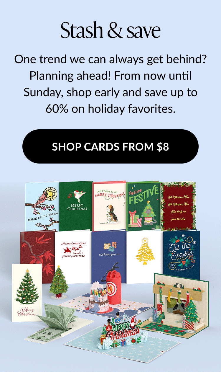 Assortment of festive holiday cards and pop-ups including Christmas trees, stockings by the fireplace, snowmen, and Merry Christmas messages, with text promoting up to 60% off on holiday favorites.