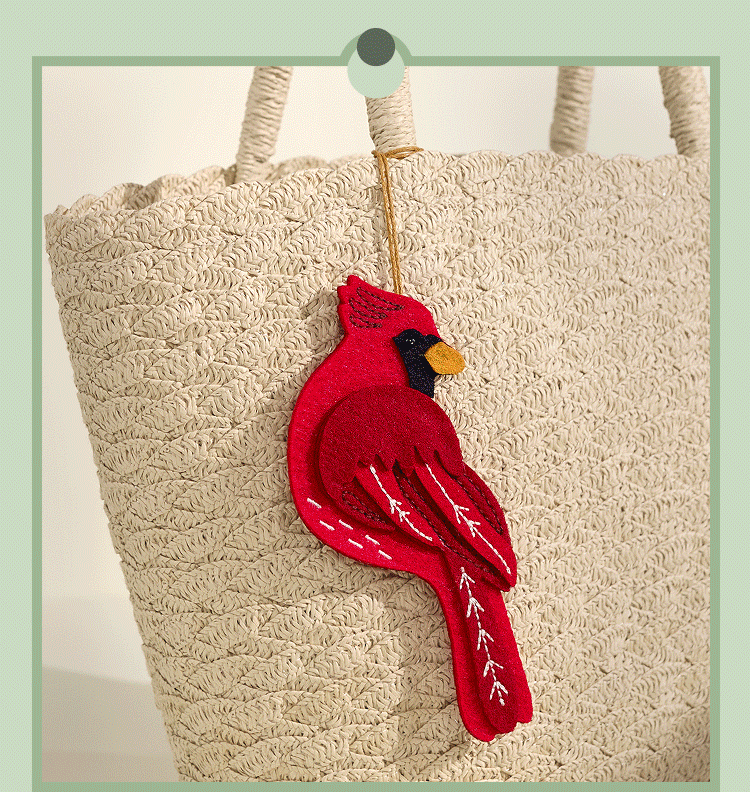 GIF of a red cardinal charm attached to a woven beige tote bag.