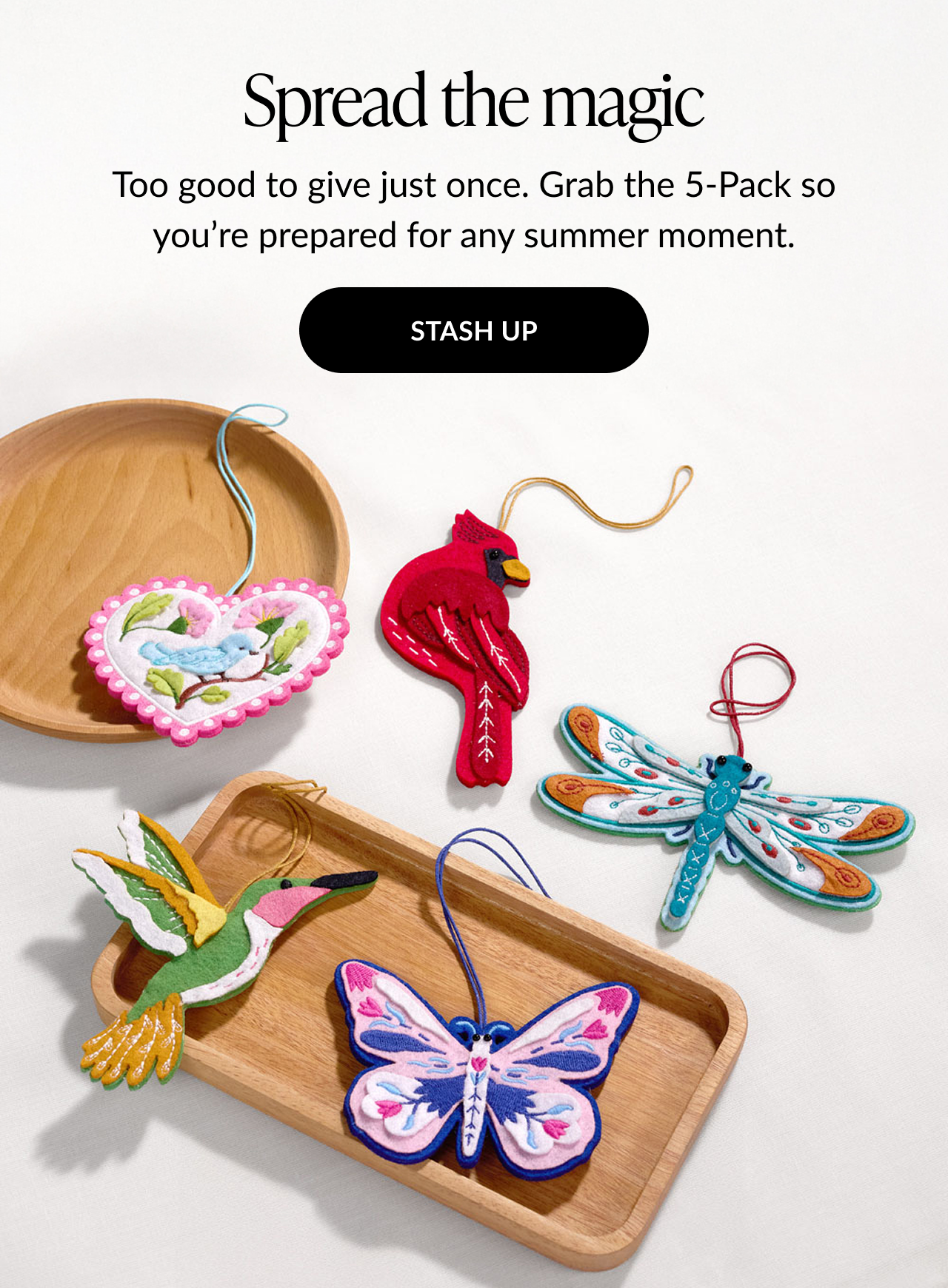 Promotional image with the headline Spread the magic, featuring a collection of five HeartFelt Charms—bluebird, cardinal, dragonfly, hummingbird, and butterfly—displayed on wooden trays.