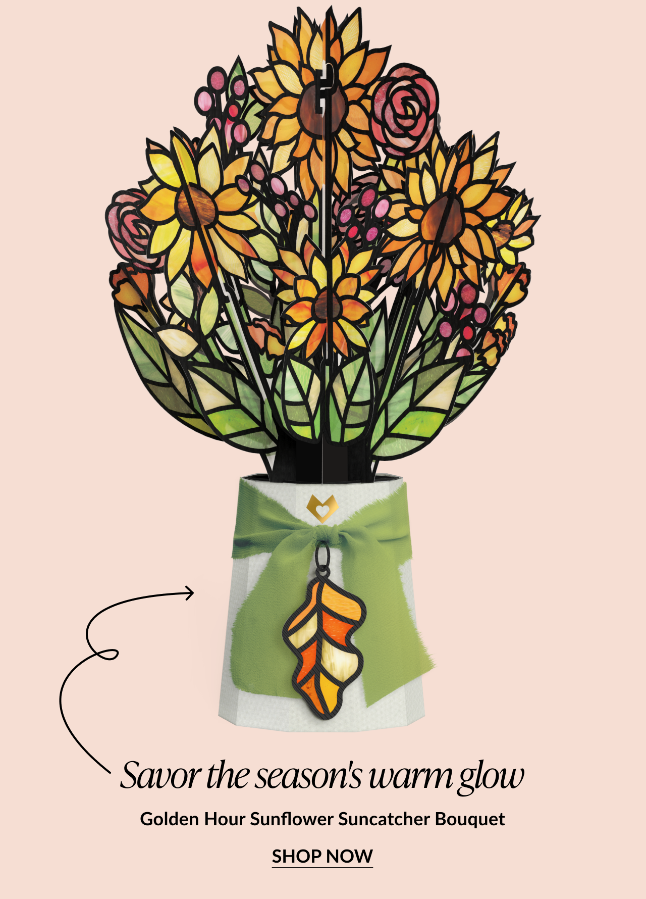 Golden Hour Sunflower Suncatcher Bouquet featuring a vibrant stained-glass style pop-up bouquet with yellow sunflowers and a green ribbon tied around the base, adorned with an autumn leaf charm, and “Shop Now” button.