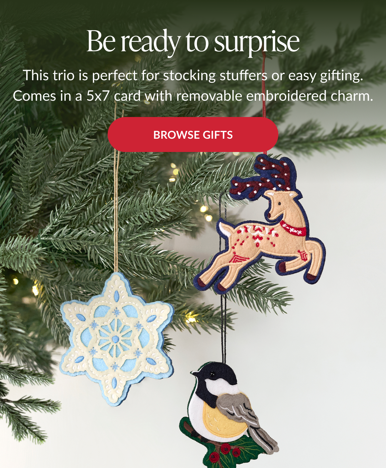 Embroidered reindeer, snowflake, and bird ornaments hanging from a Christmas tree with Browse Gifts button