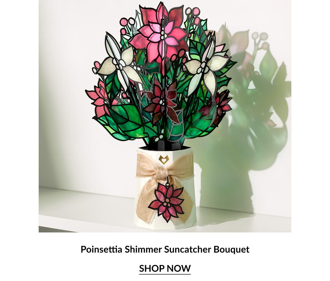 Poinsettia Shimmer Suncatcher Bouquet with pink, red, and cream flowers in a gold ribbon-wrapped vase