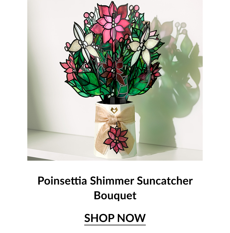 Poinsettia Shimmer Suncatcher Bouquet with pink, red, and cream flowers in a gold ribbon-wrapped vase