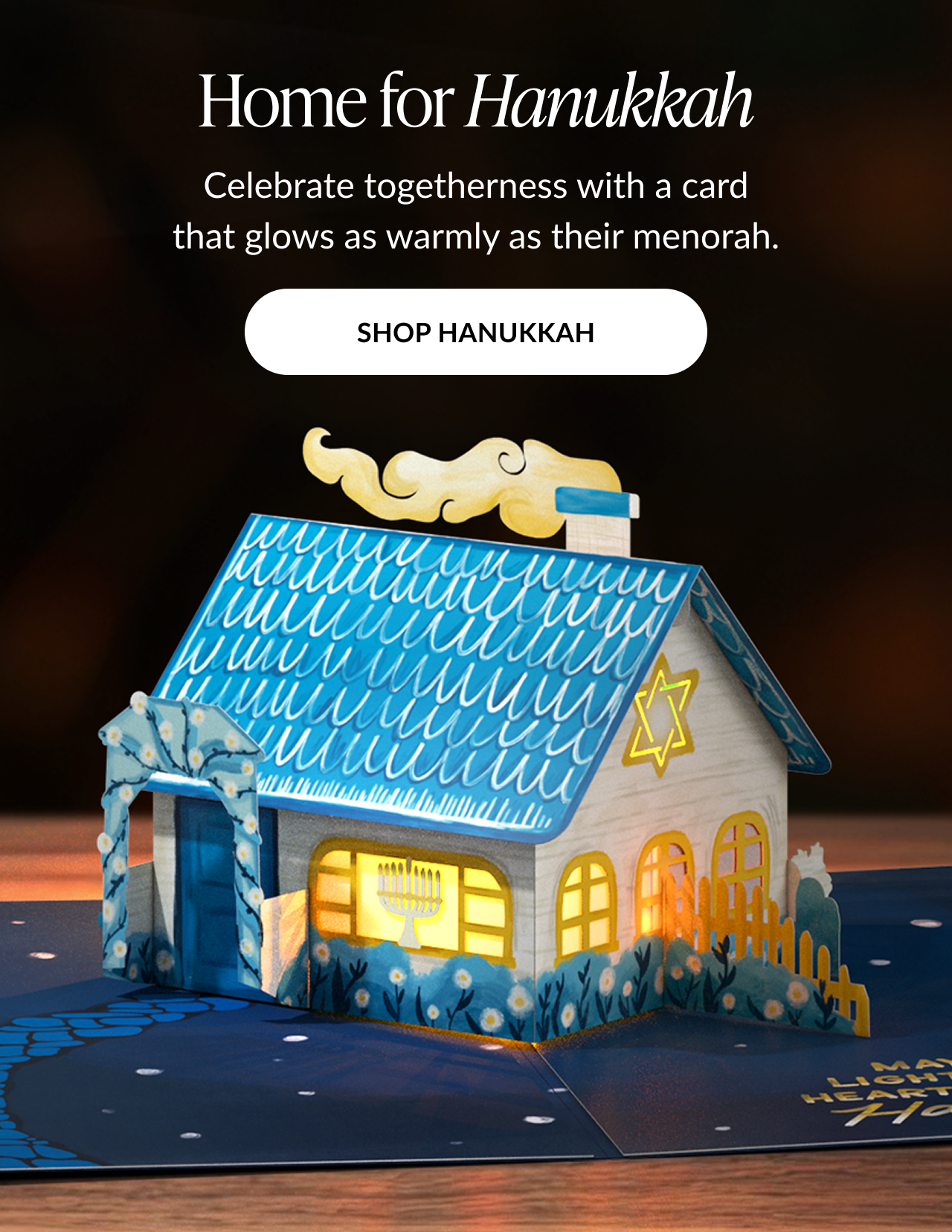 Home for Hanukkah card with glowing blue house featuring menorah and Star of David and shop Hanukkah button