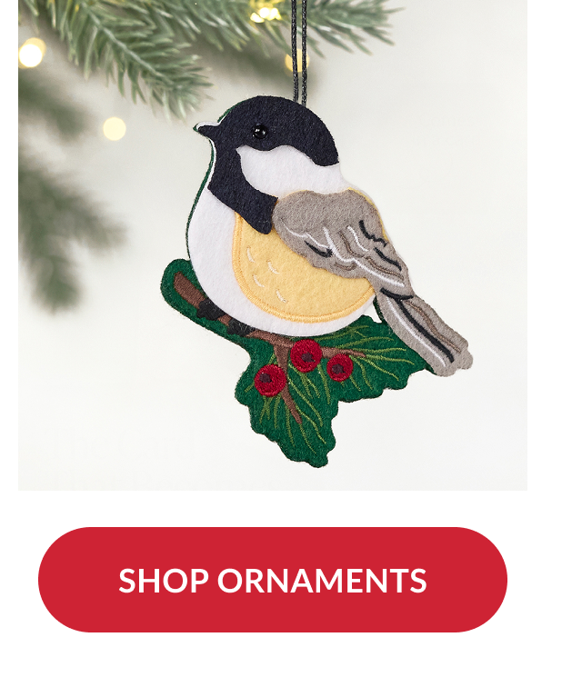 Felt bird ornament perched on holly branch hanging from tree with red button reading shop ornaments