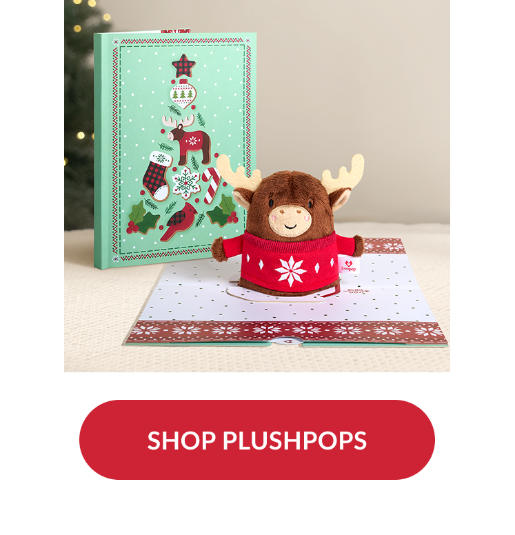 Plush moose wearing red holiday sweater popping up from card with matching mint green box decorated with festive tree design and red button reading shop plushpops