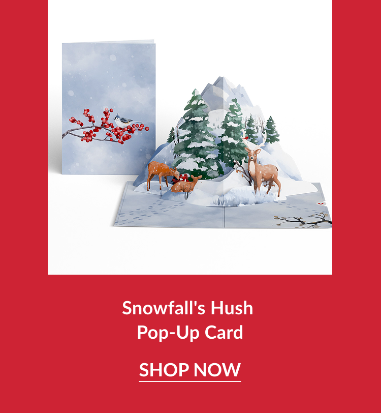 Snowfall’s Hush Pop-Up Card featuring snowy mountain scene with deer and evergreen trees beside a card showing red berries on a winter branch with shop now button
