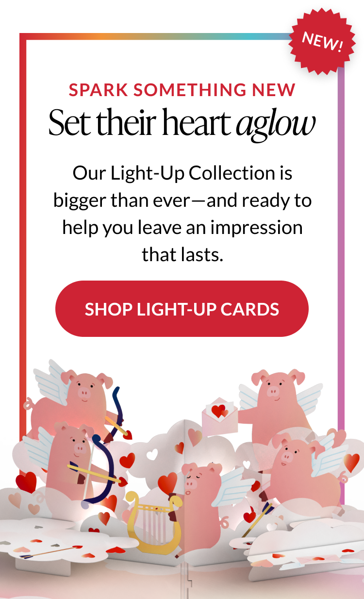 Promotional banner for Light-Up cards featuring winged pigs as cupids, glowing hearts, and Shop Light-Up Cards button