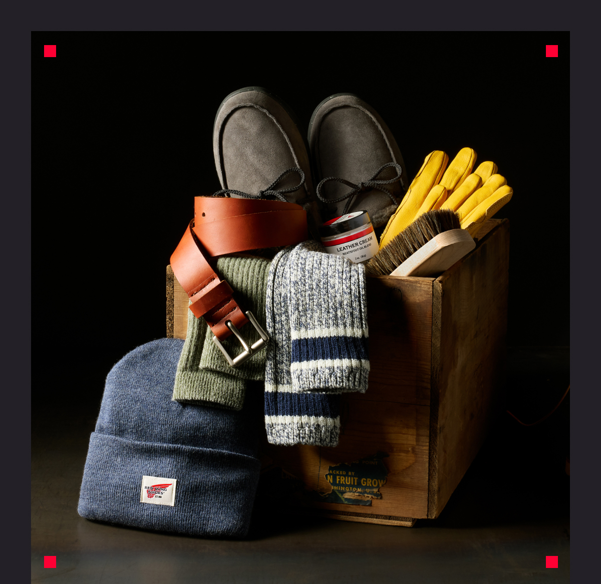 A wooden crate with variety of Red Wing accessories in it