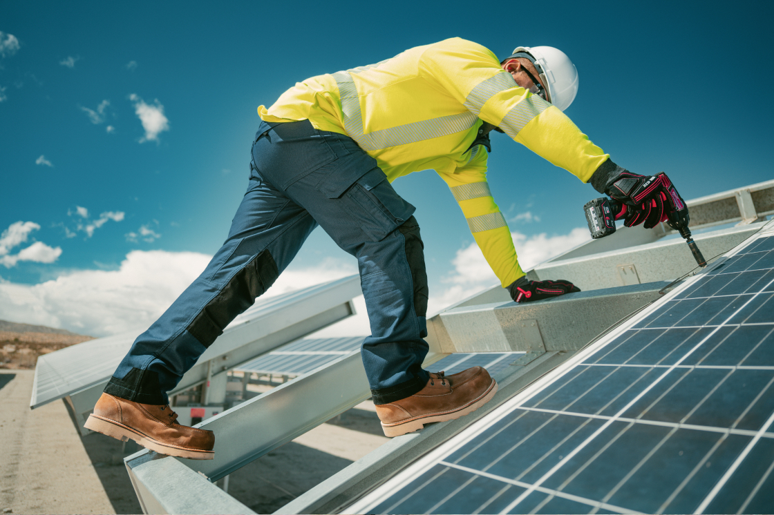Man working on a solar panel while wearing Red Wing boots