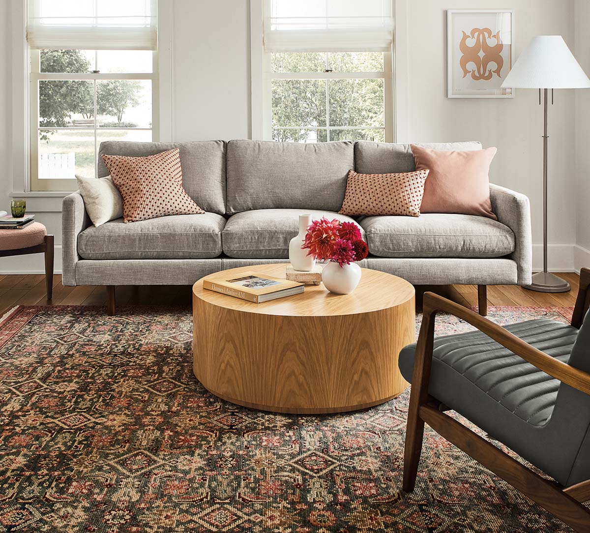 Living room with grey Jasper sofa, Callan chair, and round wood coffee table on patterned rug.