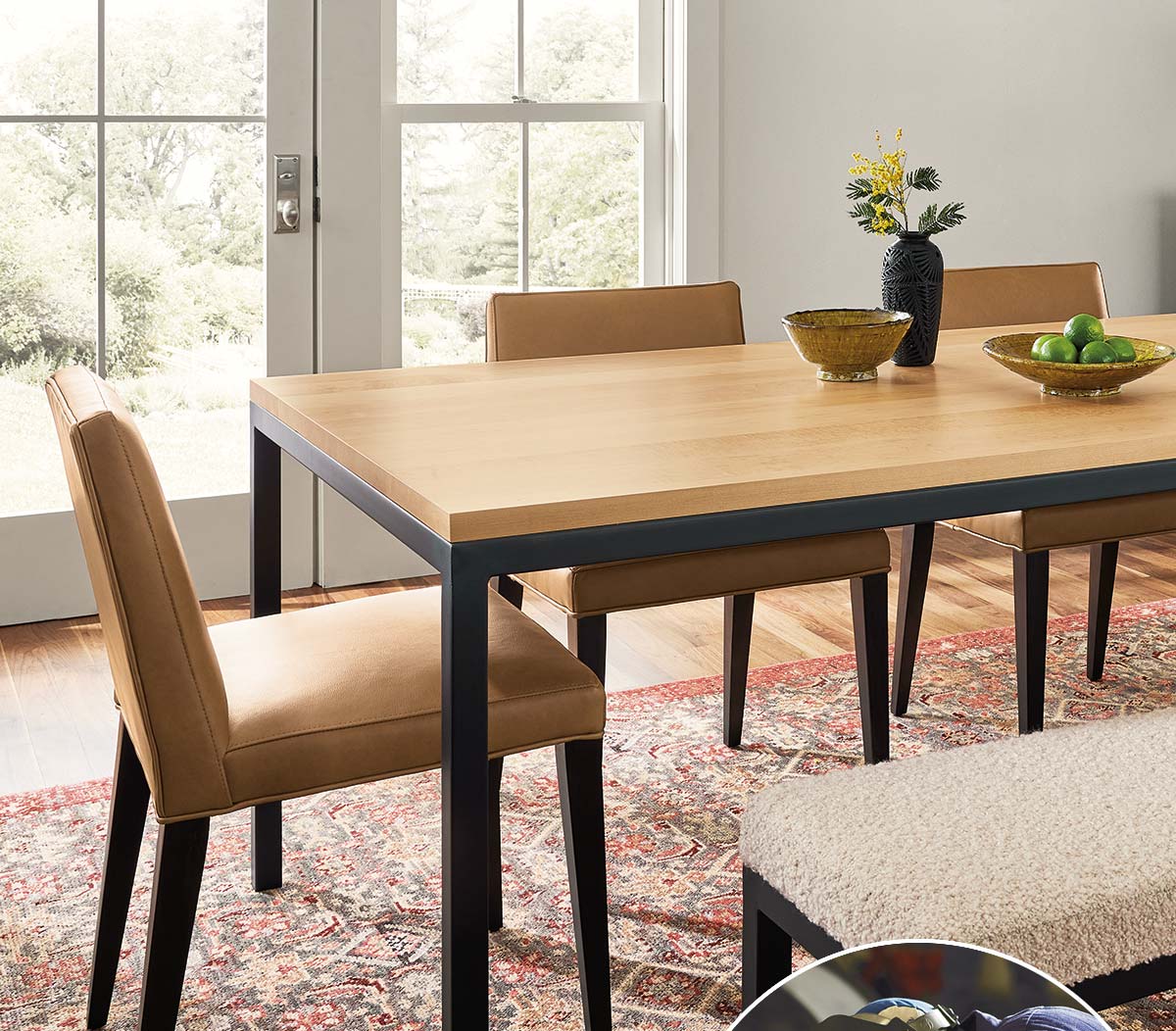 Dining room with Parsons table, tan leather chairs, patterned rug, and glass door to backyard view.