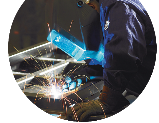 Close-up of welder in protective gear using torch to fuse metal beams with bright sparks flying.