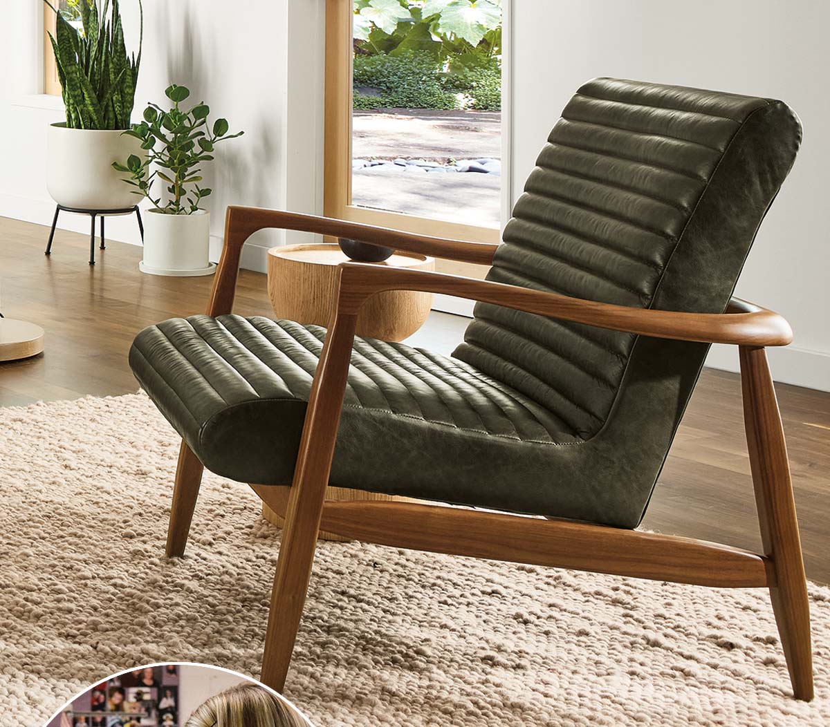 Callan chair with dark leather seat and walnut frame on textured rug beside large window and potted plants.
