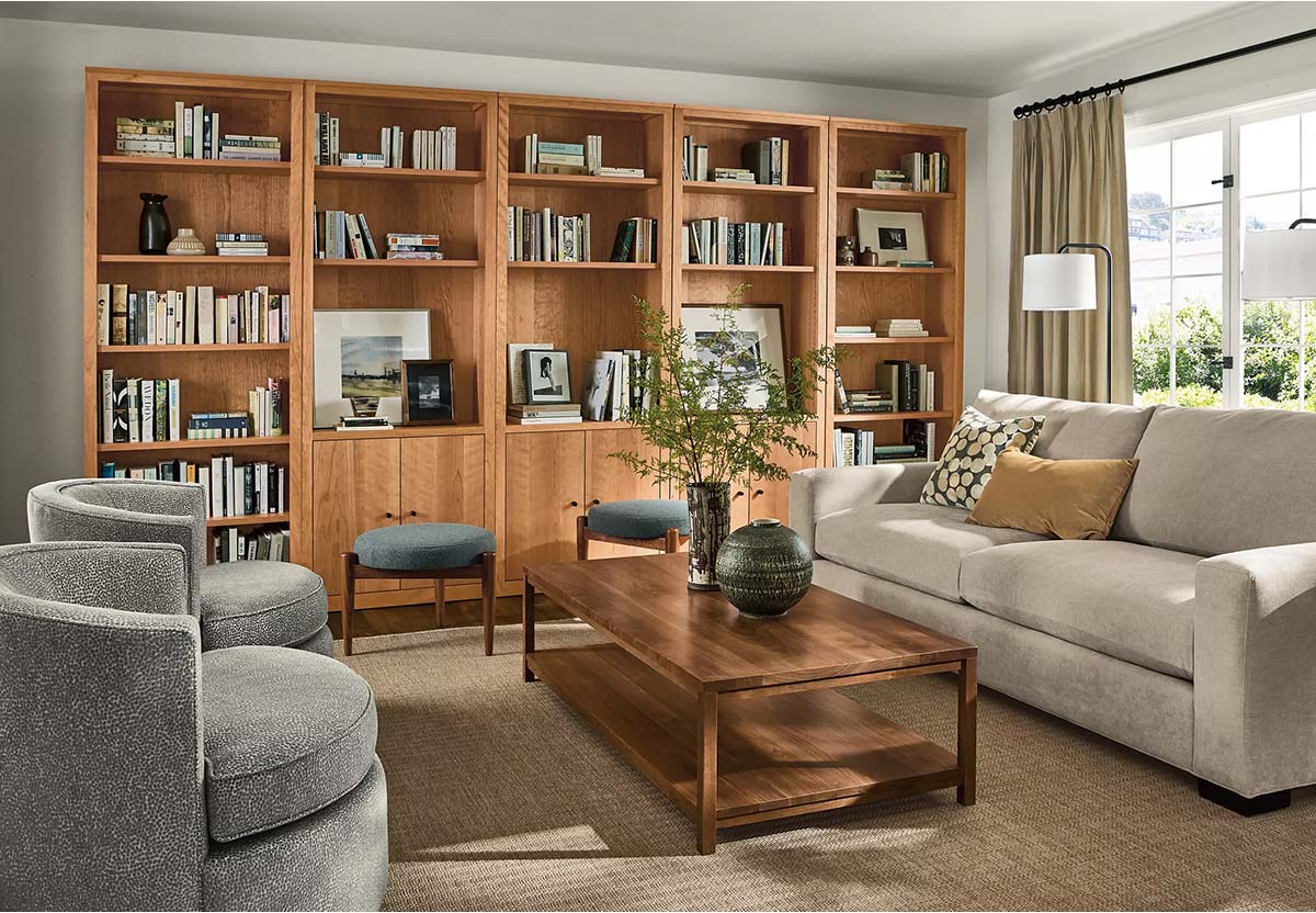 Living room with Metro sofa, coffee table, round swivel chairs and Woodwind bookcases filled with books and framed art.
