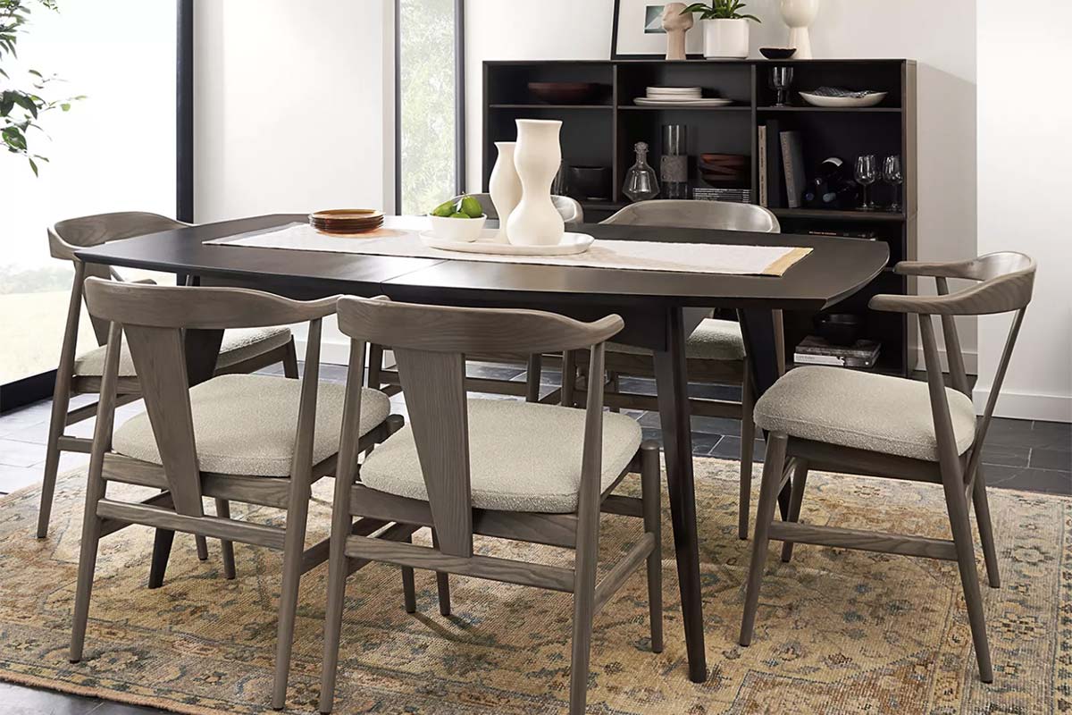 Ventura dining table with six chairs styled with a runner and ceramics, backed by a dark storage cabinet.