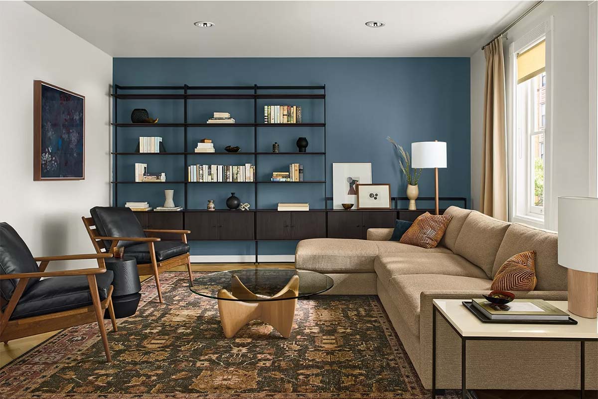 Linger sectional with accent pillows and black chairs next to Beam shelving filled with books, art and decorative objects.