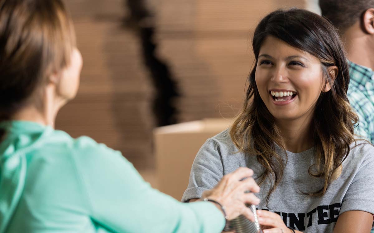 Volunteers passing canned goods while smiling during a community event.