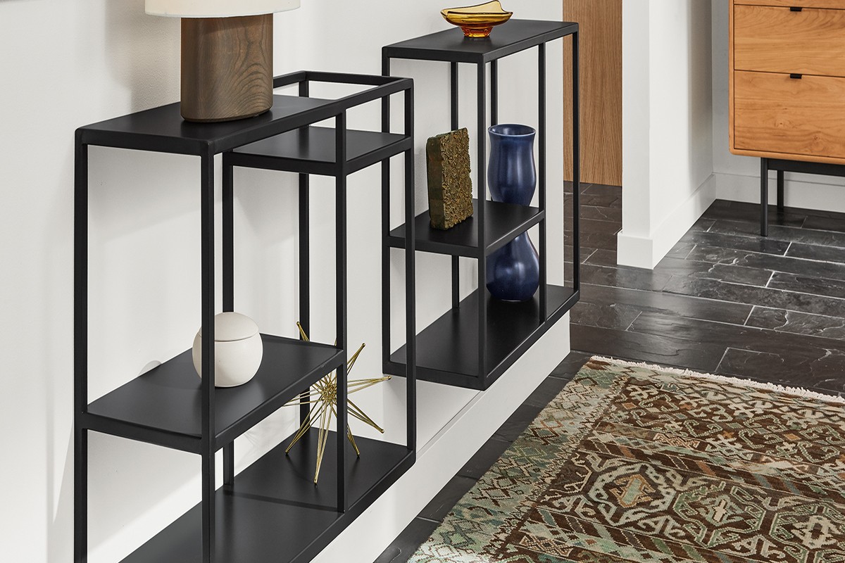 Pair of black Foshay shelves with open frames and staggered shelves, holding sculptural decor and glass vases.