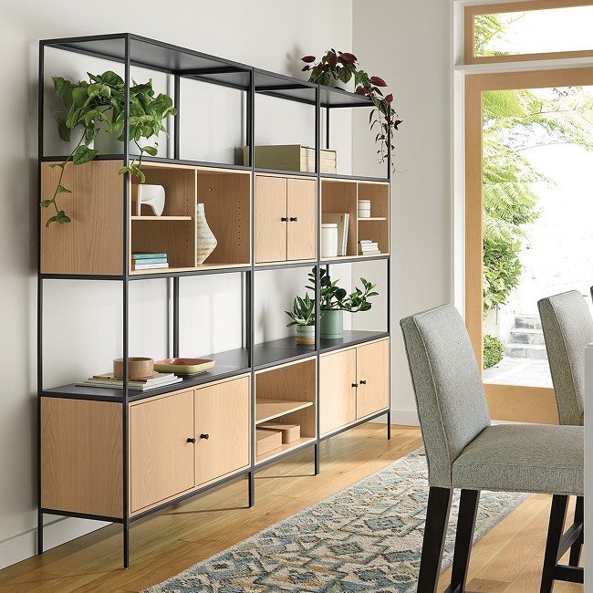 Slim wall unit with black frame and oak cabinets, styled with books, ceramics, and greenery in a dining space.